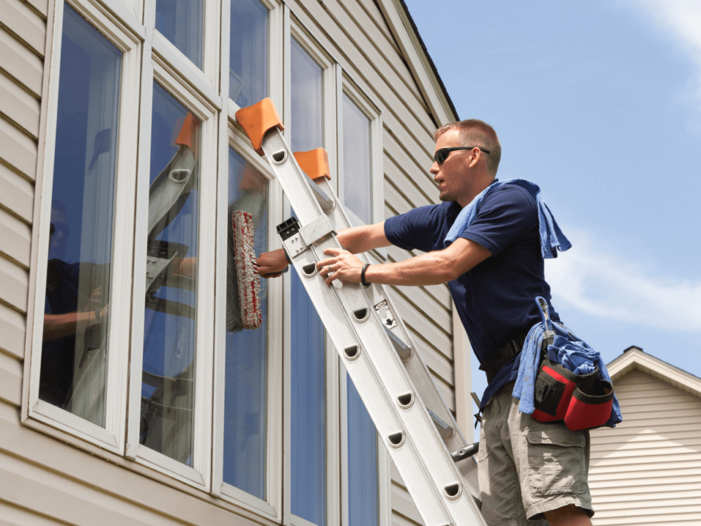 man on ladder cleaning residential windows wide